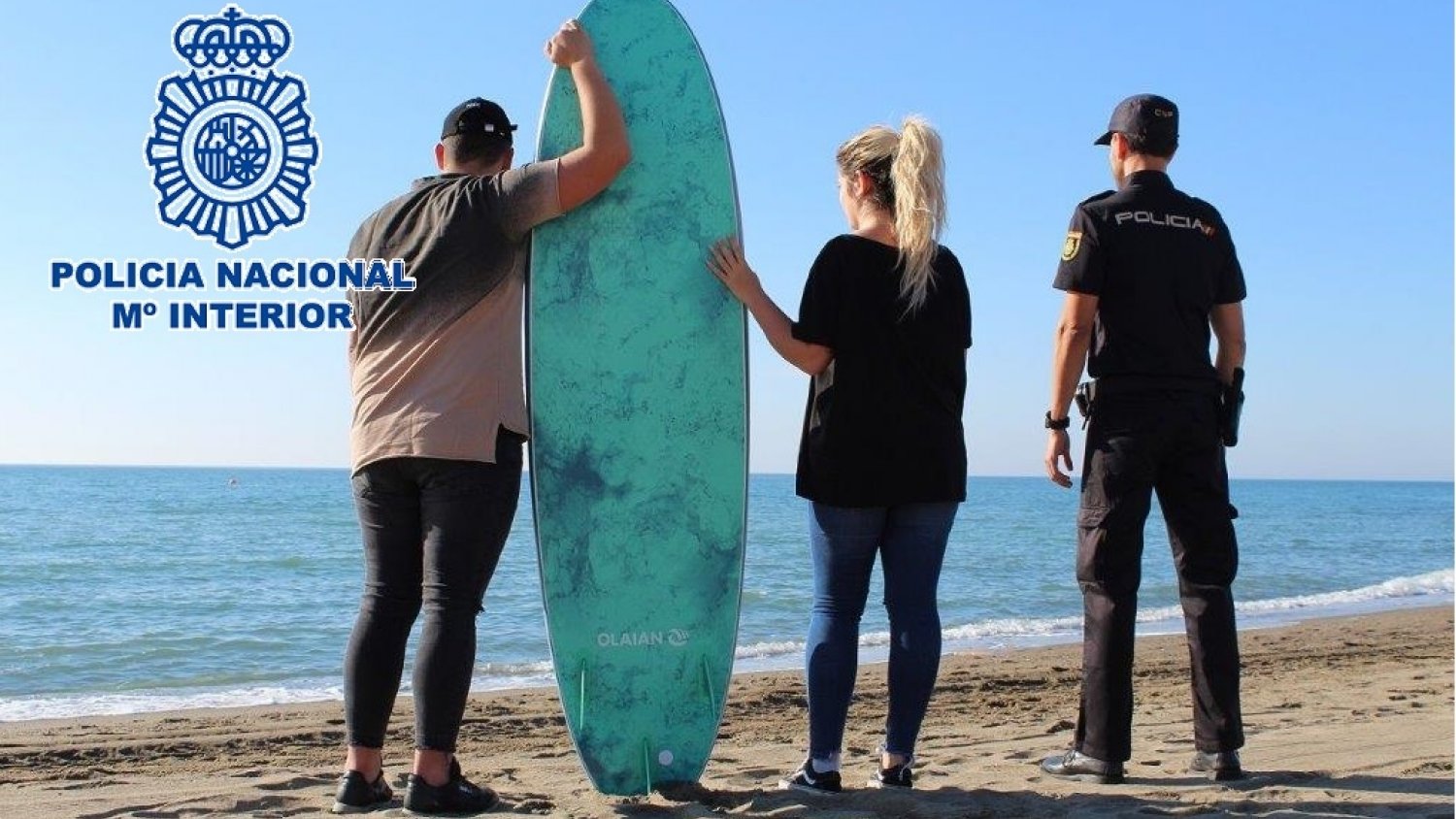 Un agente de la Policía Nacional rescata en su tabla de surf a dos bañistas a punto de ahogarse