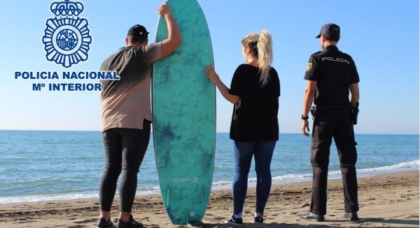 Un agente de la Policía Nacional rescata en su tabla de surf a dos bañistas a punto de ahogarse